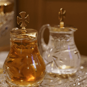 Crystal containers with holy water and oil on a lace cloth.