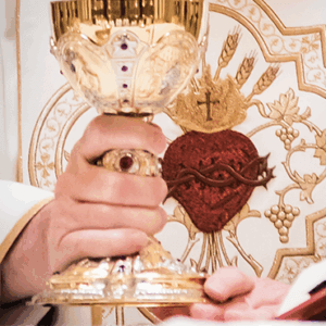 Priest holding golden chalice during Catholic Mass with Sacred Heart symbol