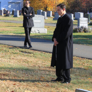 Legionary priests praying in a cemetery during the All Souls Novena