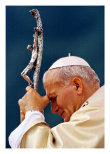 Pope John Paul II praying with a crucifix staff.